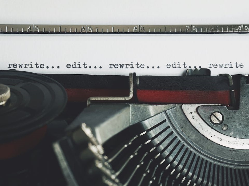 Close-up of a page in a typewriter with the words '... rewrite... edit...' repeating